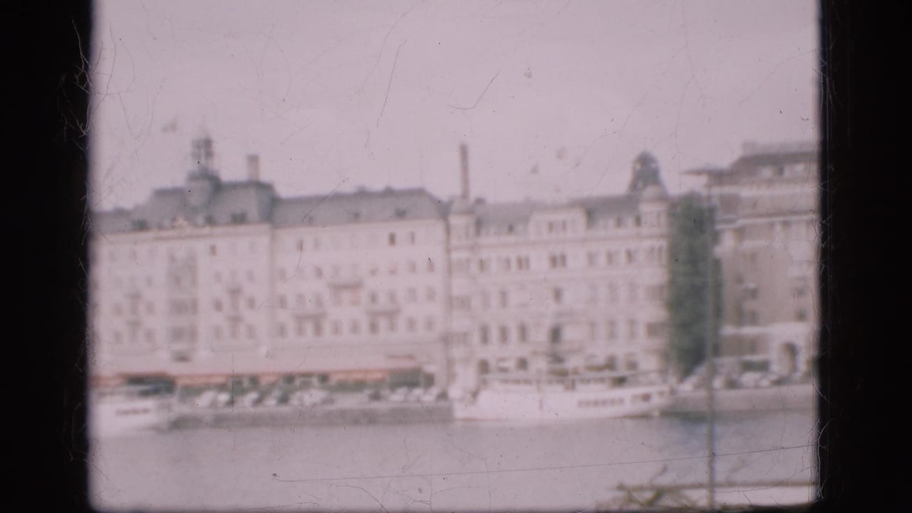 1975 Denmark home-movie frame showing multi-story buildings along a waterfront, seen softly from across the water.