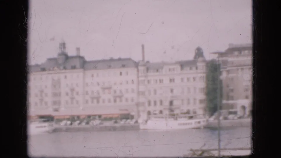 1975 Denmark home-movie frame showing multi-story buildings along a waterfront, seen softly from across the water.
