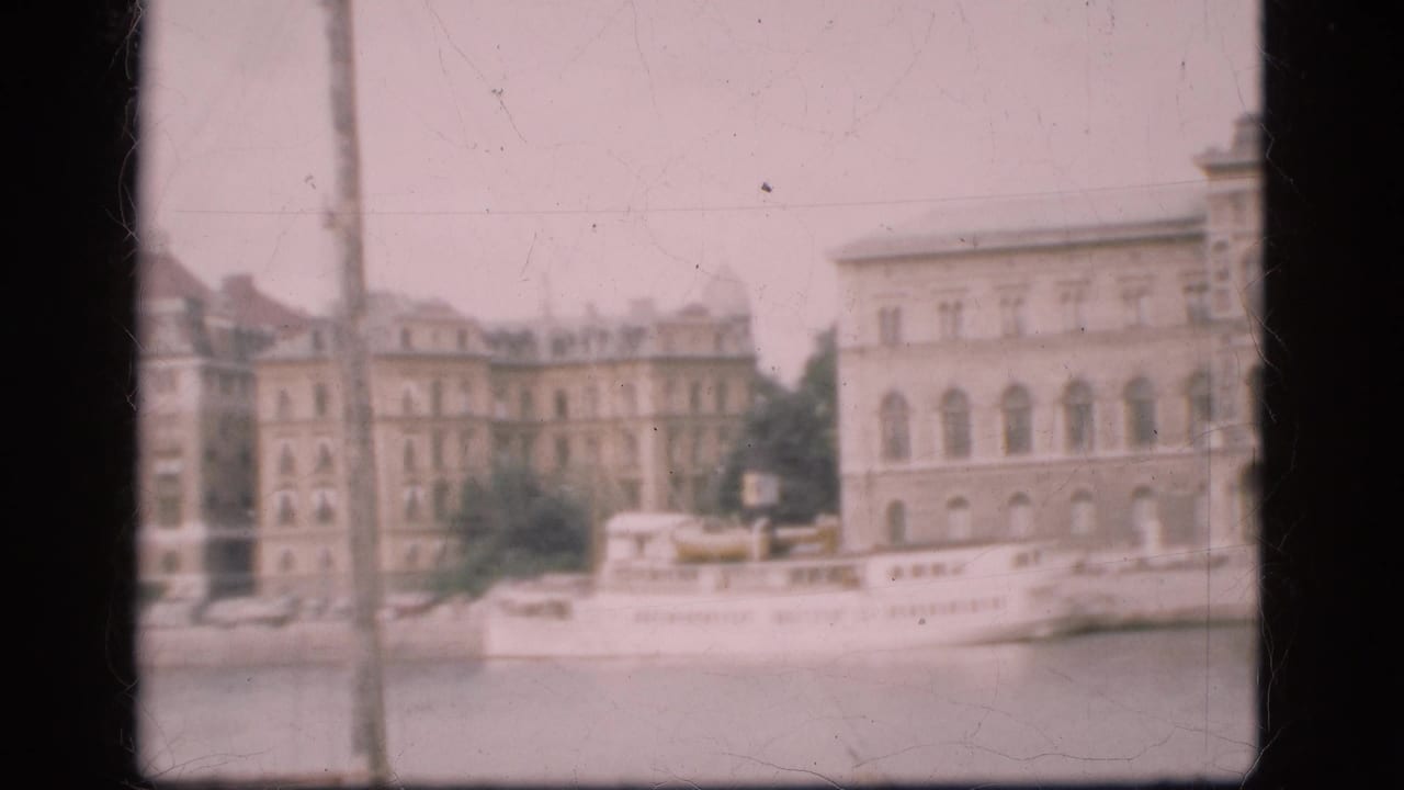 Soft 8mm view of a Danish waterfront with a white passenger boat along the quay and multi-story buildings behind it.