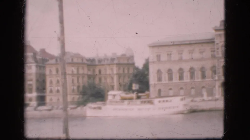 Soft 8mm view of a Danish waterfront with a white passenger boat along the quay and multi-story buildings behind it.