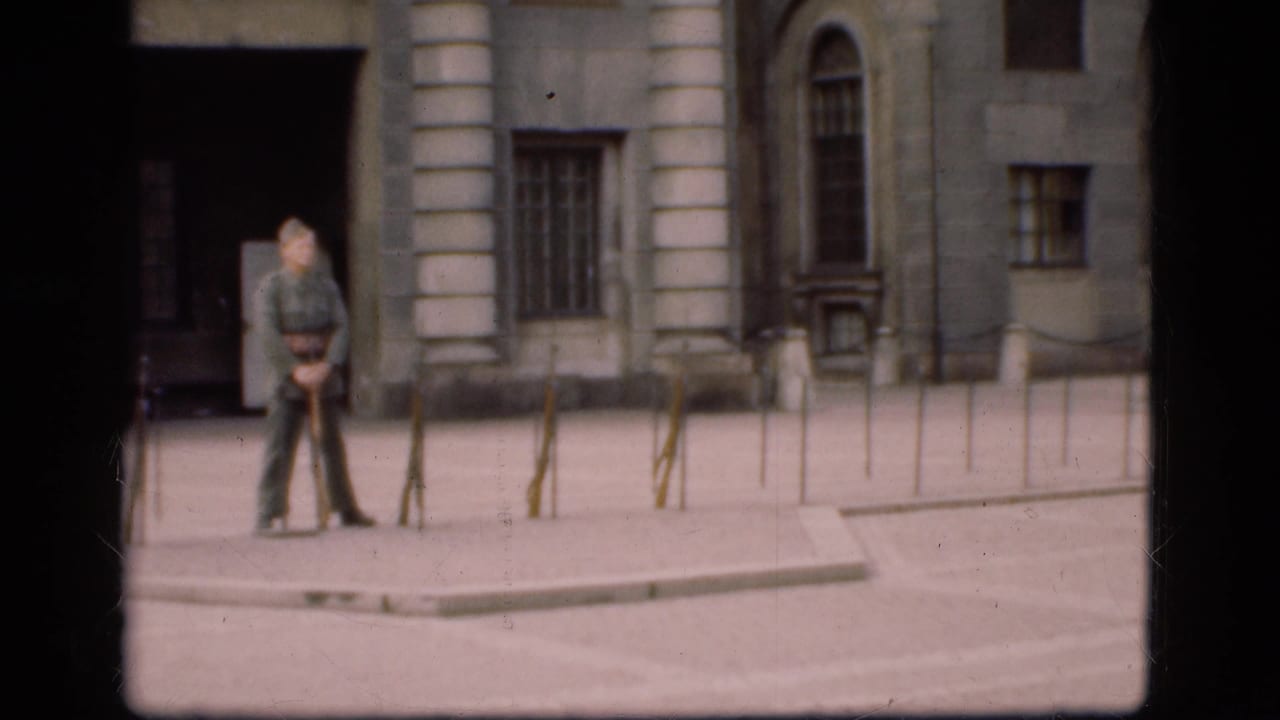 1975 Denmark 8mm frame with a soldier standing near a dark doorway and stone columns in a formal courtyard.