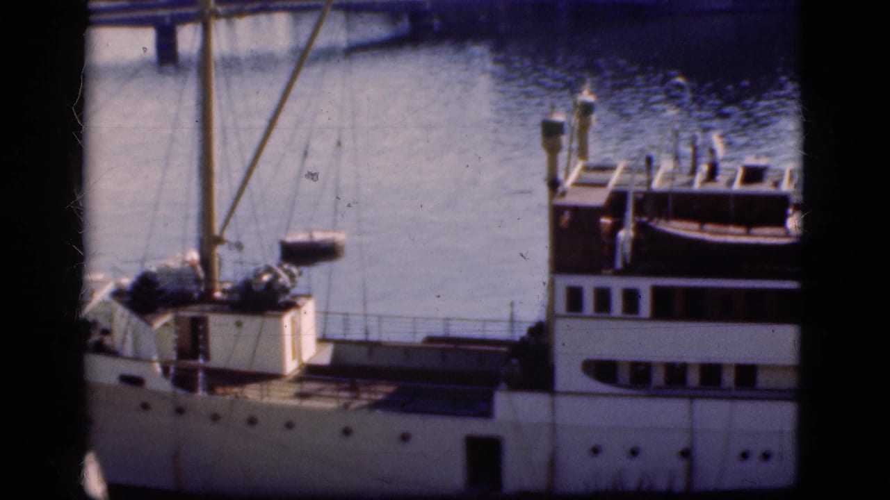 1975 Denmark footage frame of a docked white passenger ship viewed from above, with mast rigging and harbor water in the background.