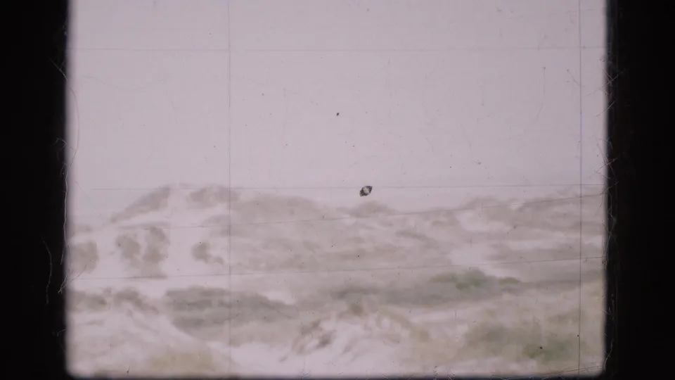 A soft 8mm view of snow-covered Danish terrain with low hills and a washed-out winter sky.