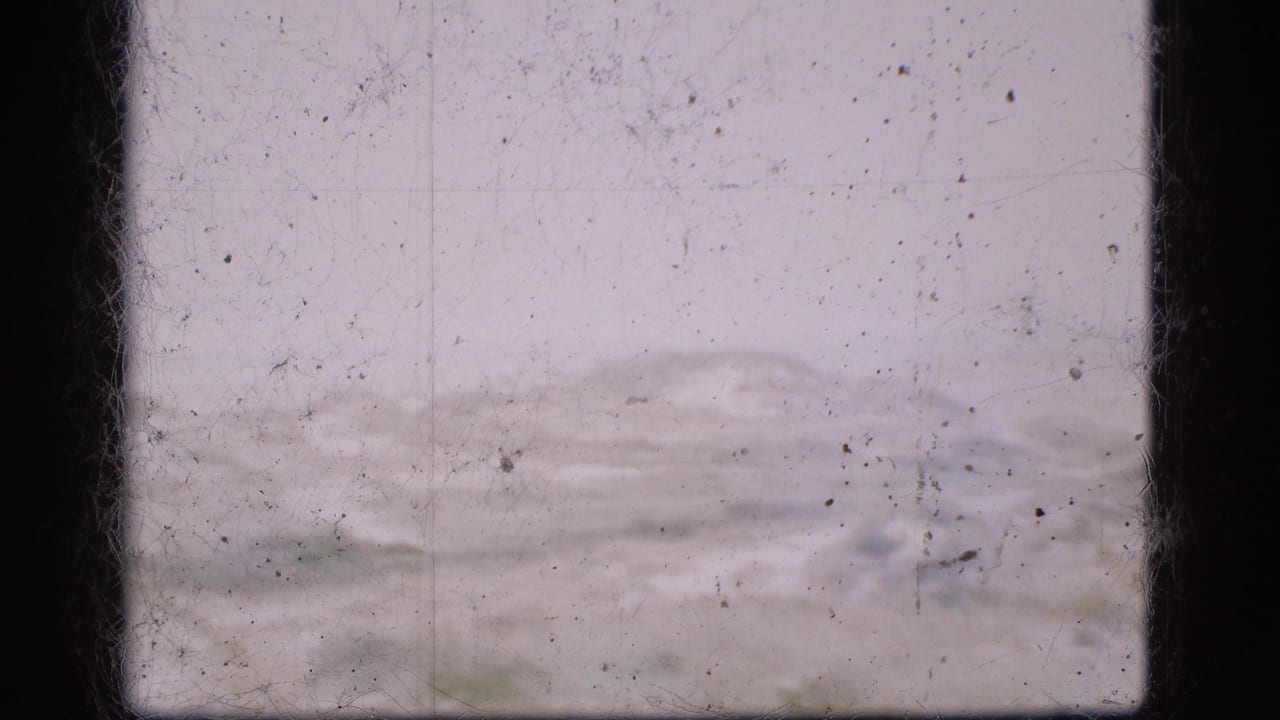 Low rolling terrain under a pale sky with dust and scratches across the film frame.