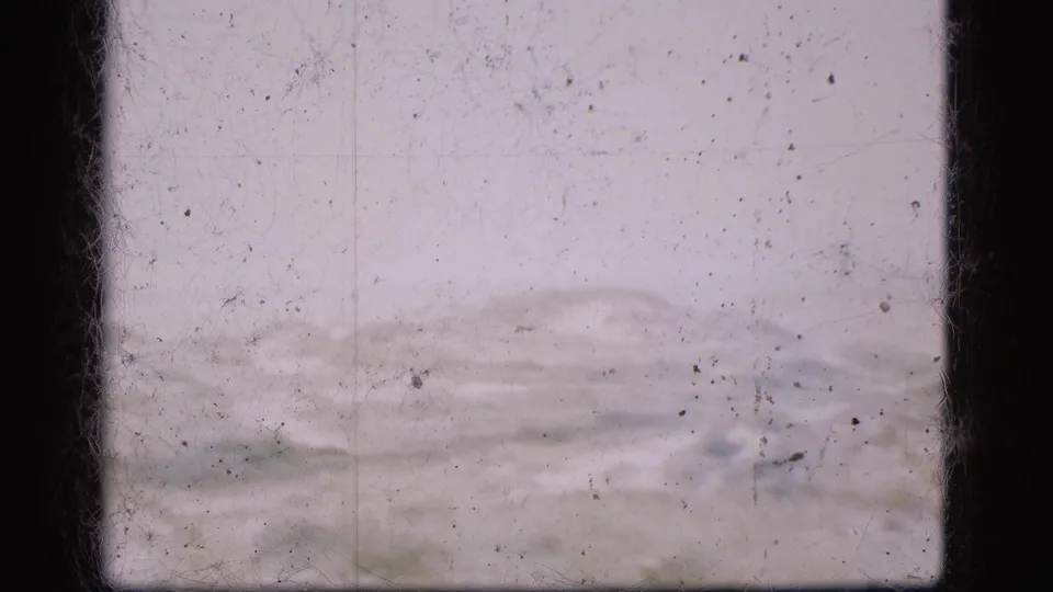 1975 Denmark 8mm frame of a low, distant hilly landscape, softened by exposure and marked by dust, scratches, and contact-sheet borders.