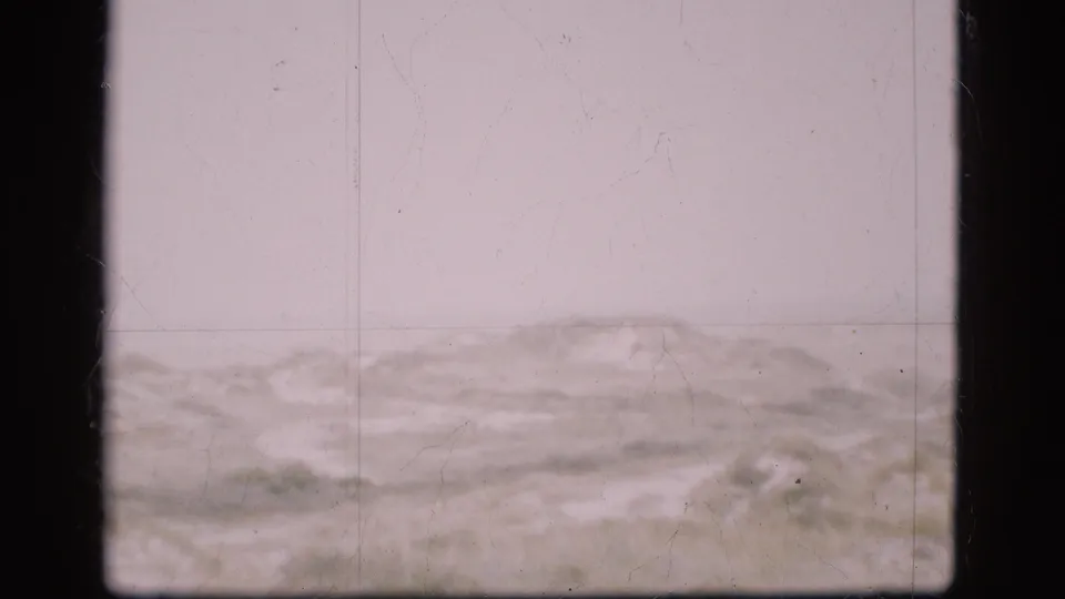 1975 Denmark 8mm frame showing a muted overcast sky and low barren ground, with soft focus and visible film wear.