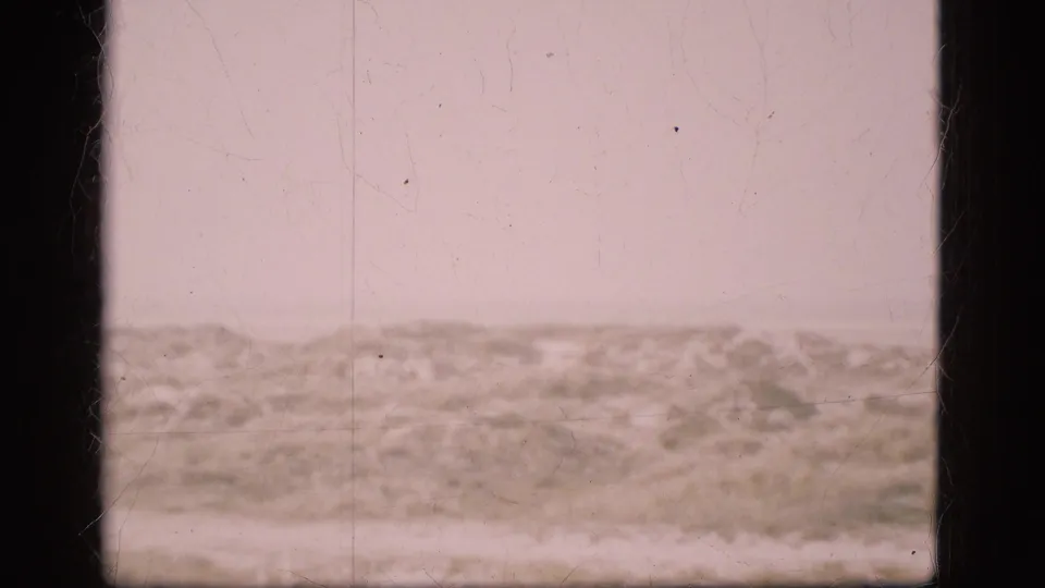 1975 Denmark 8mm view of a low windswept dune ridge beneath a pale sky, with soft focus, dust, scratches, and heavy frame borders.