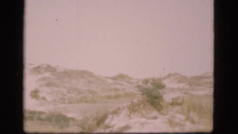 1975 Denmark 8mm frame of dune terrain with sparse vegetation and visible film gate edges.