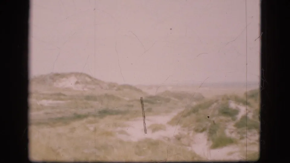 1975 Denmark 8mm frame of rolling coastal dunes, sparse vegetation, and a muted horizon line.