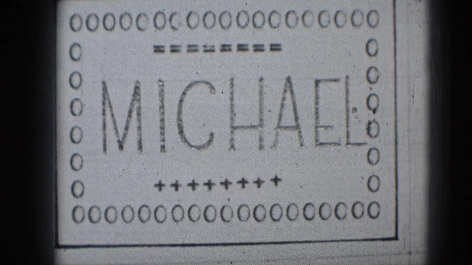 Middletown-era 8mm frame showing the MICHAEL title card, decorative marks, soft focus, and visible film grain.