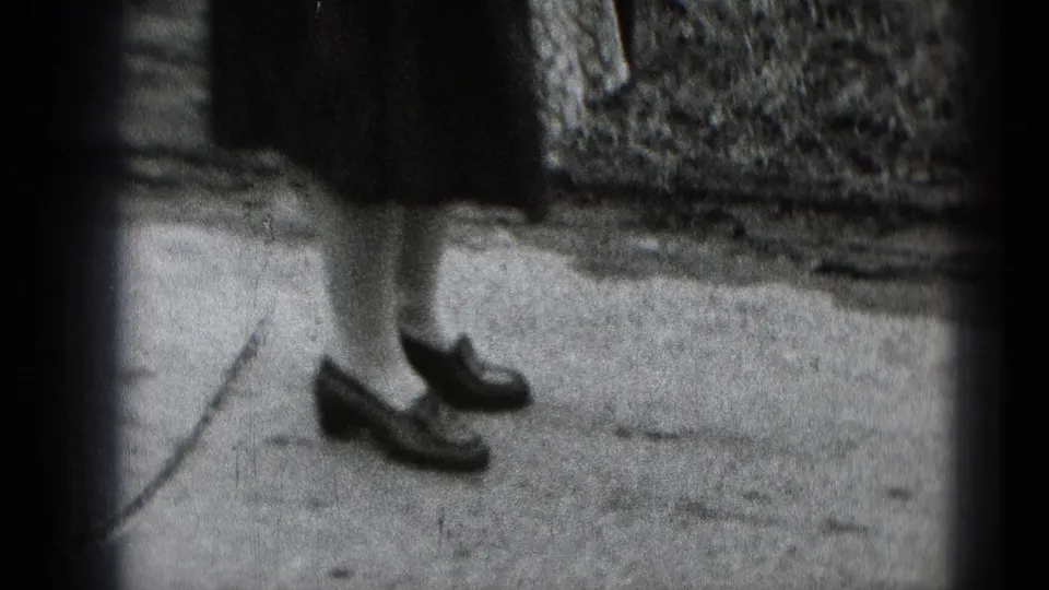 Cropped 8mm frame from Middletown, Pennsylvania, showing a woman's lower legs and dark shoes on a concrete path.