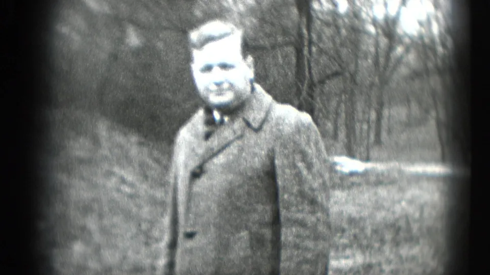 Adult man in a heavy winter coat and tie faces the camera in a wooded Middletown, Pennsylvania home-movie frame from 1948.