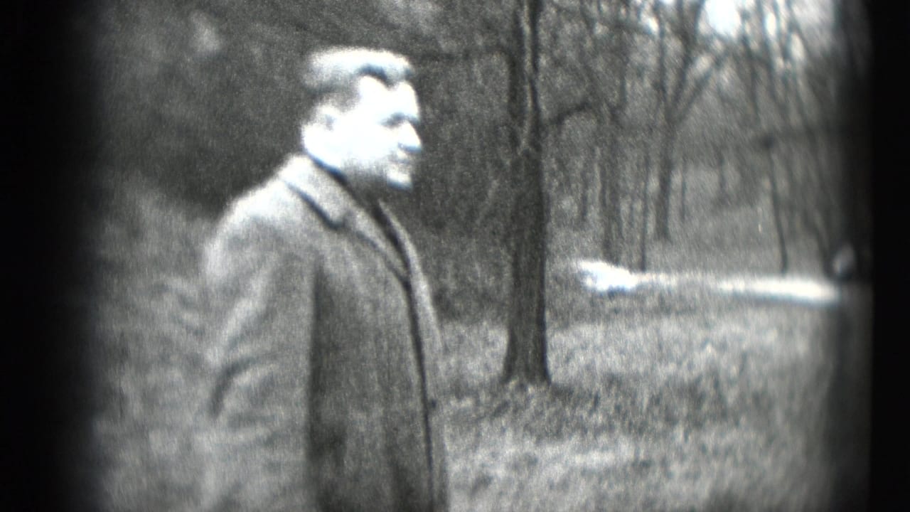 The man turns to the side in a heavy coat, with bare trees and open ground behind him in the 1948 Middletown footage.
