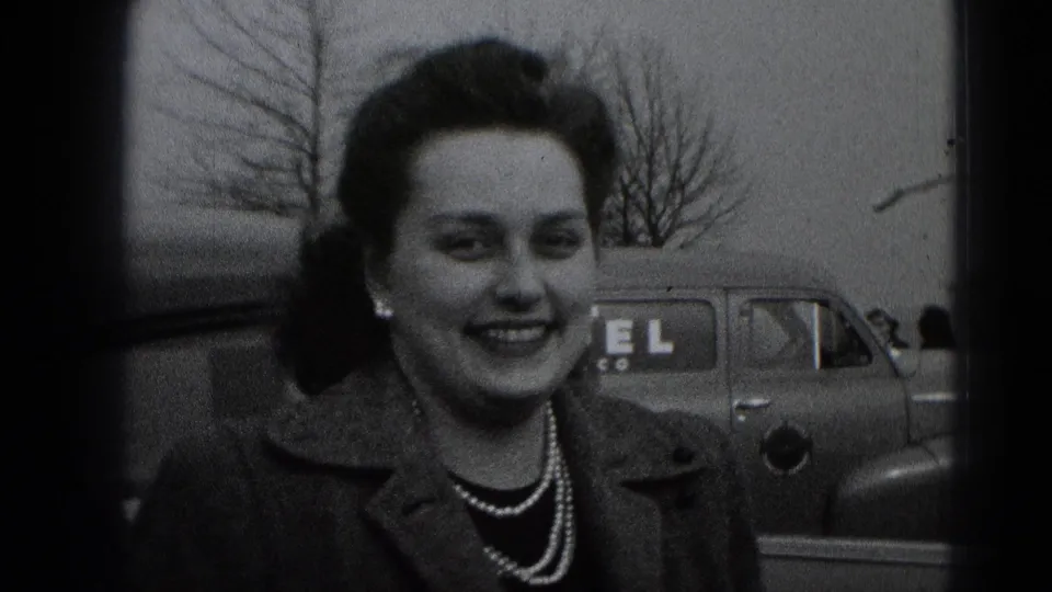Smiling woman in late-1940s Middletown, Pennsylvania home-movie footage, with a parked car and bare trees behind her.