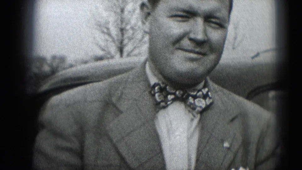 In Middletown, Pennsylvania, a smiling adult man in a suit and patterned bow tie sits near a car with bare trees in the background.