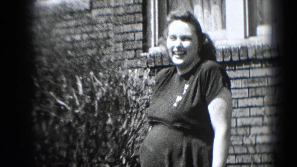 A closer 1948 Middletown frame shows the pregnant woman smiling near a brick wall and window after the yard telephone moment.