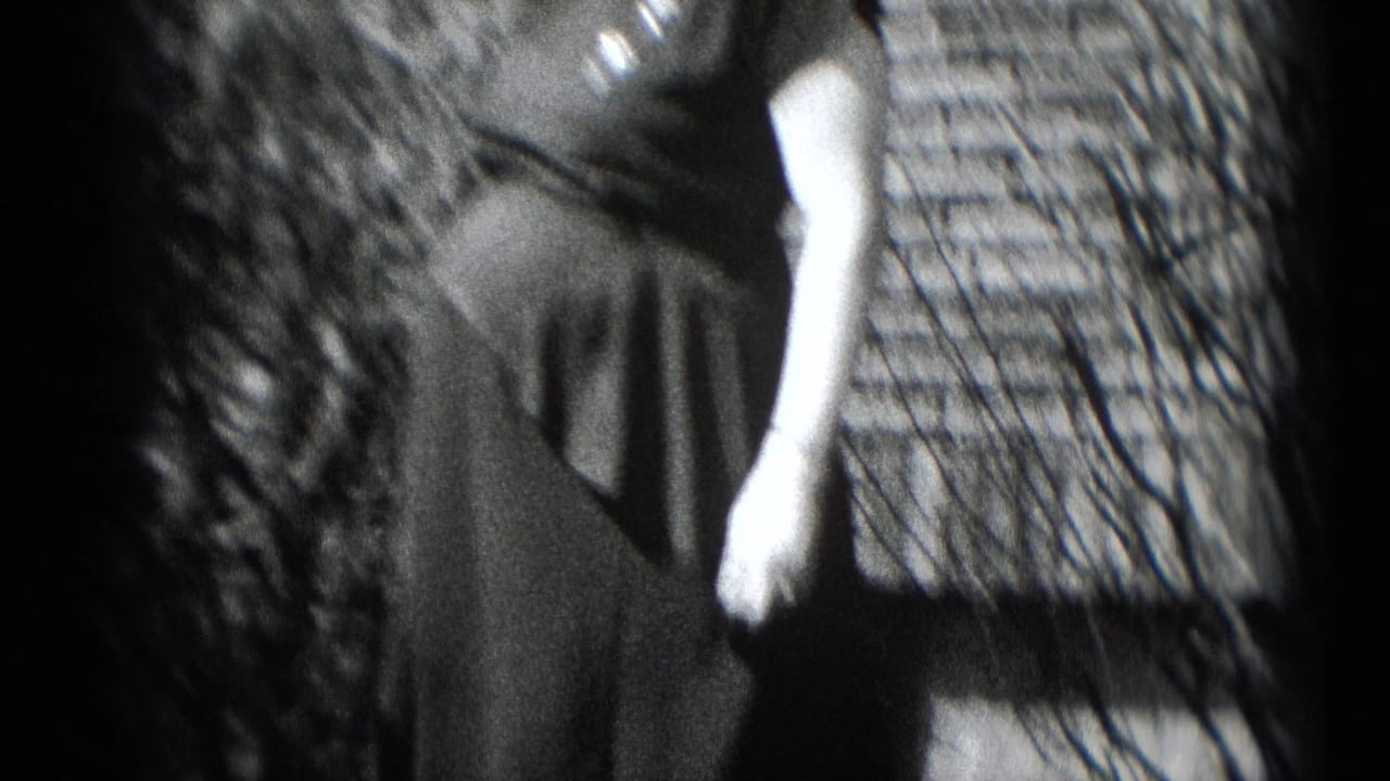 A woman in a dark dress is partly seen outdoors in Middletown, Pennsylvania, in 1948, with shrubs and house siding nearby.