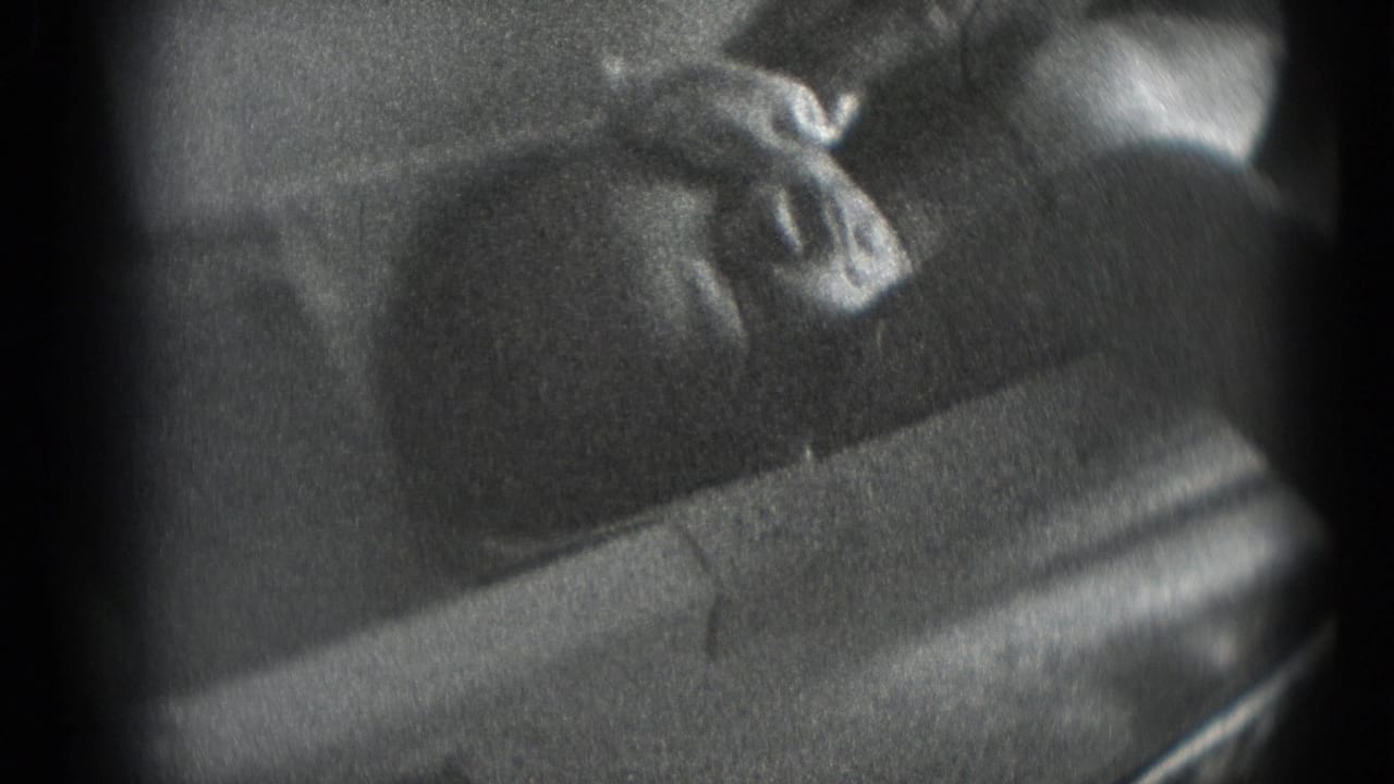 Newborn lying on soft cloth as an adult hand touches or wipes the face.