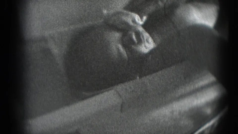 Black-and-white 8mm close-up from a Middletown, Pennsylvania home movie showing a newborn resting while an adult hand tends the face.