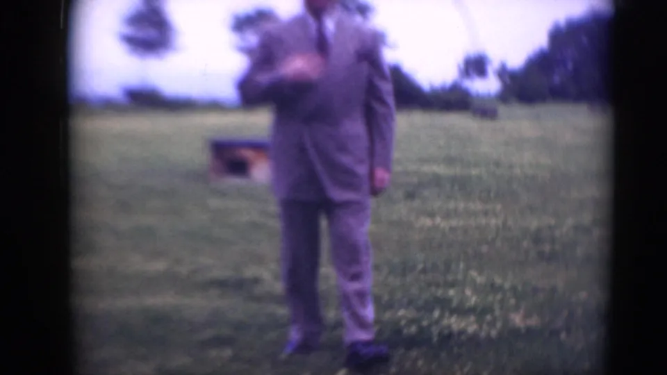 Adult man in a gray suit stands outdoors in a grassy Middletown, Pennsylvania field, with trees and a small low structure behind him.