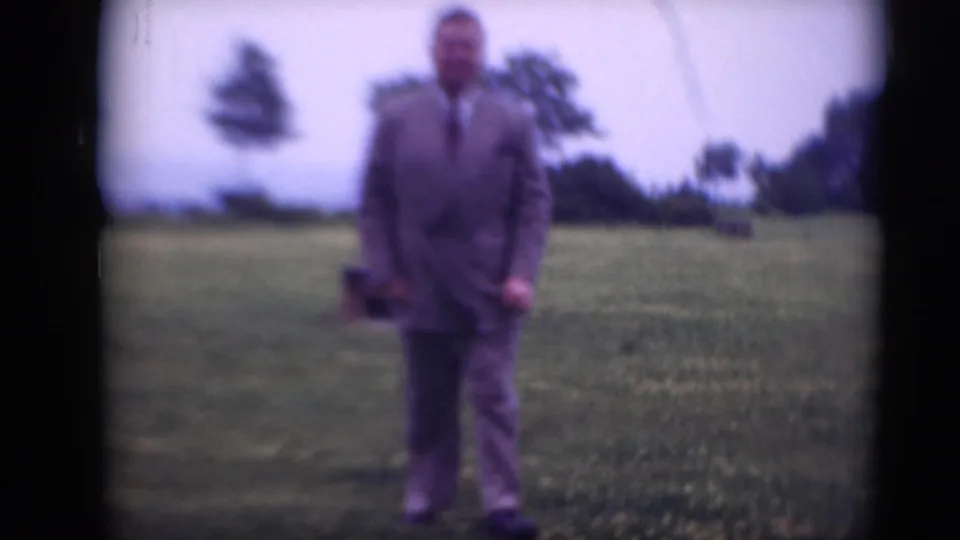 Adult man in a gray suit and tie moves slightly toward the camera in soft-focus 8mm footage from Middletown, Pennsylvania.