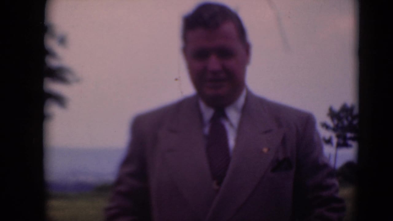 Suited adult man stands for the camera in rural Middletown, Pennsylvania, with soft 8mm color and focus.