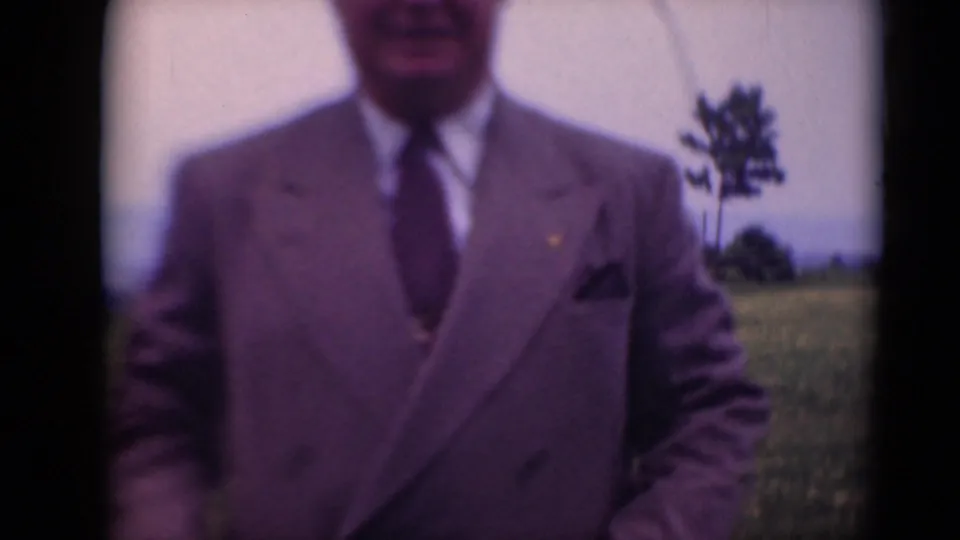 Closer 1948 8mm frame of the man's suit, tie, and torso as he stands outdoors in Middletown, Pennsylvania.