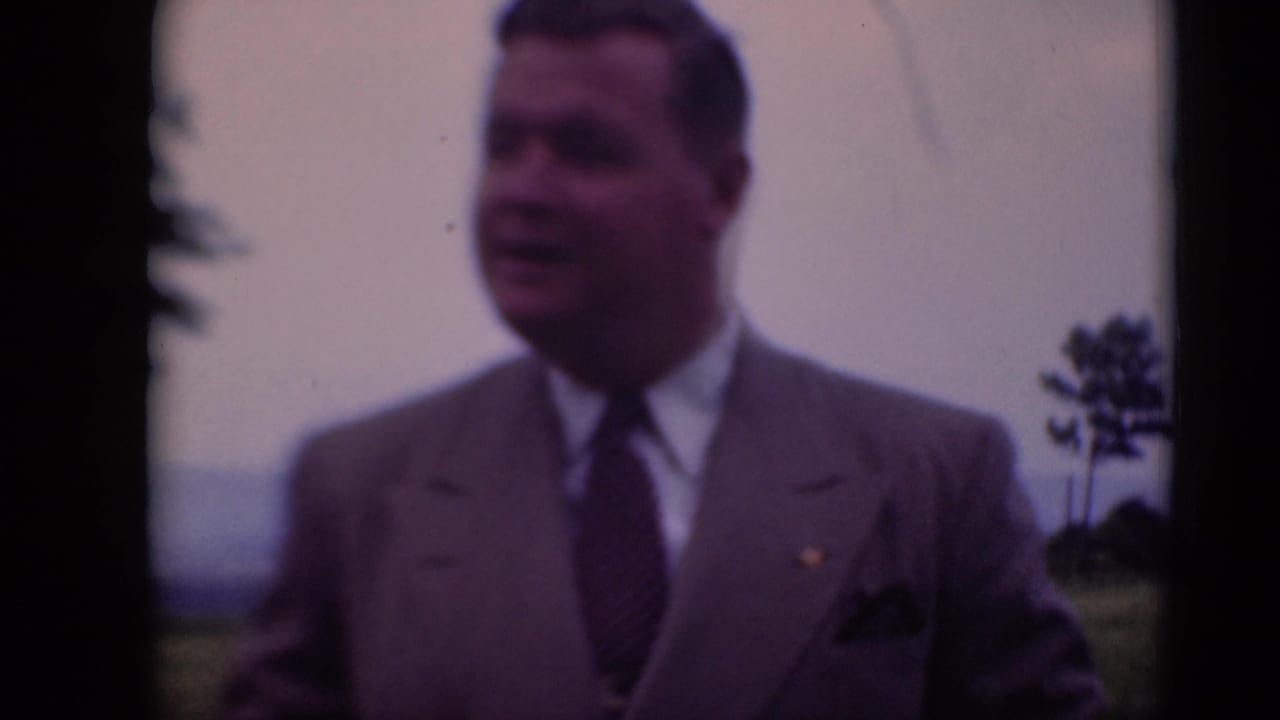 A man in a light suit and patterned tie stands in a field near Middletown, Pennsylvania, in late-1940s 8mm home-movie footage.