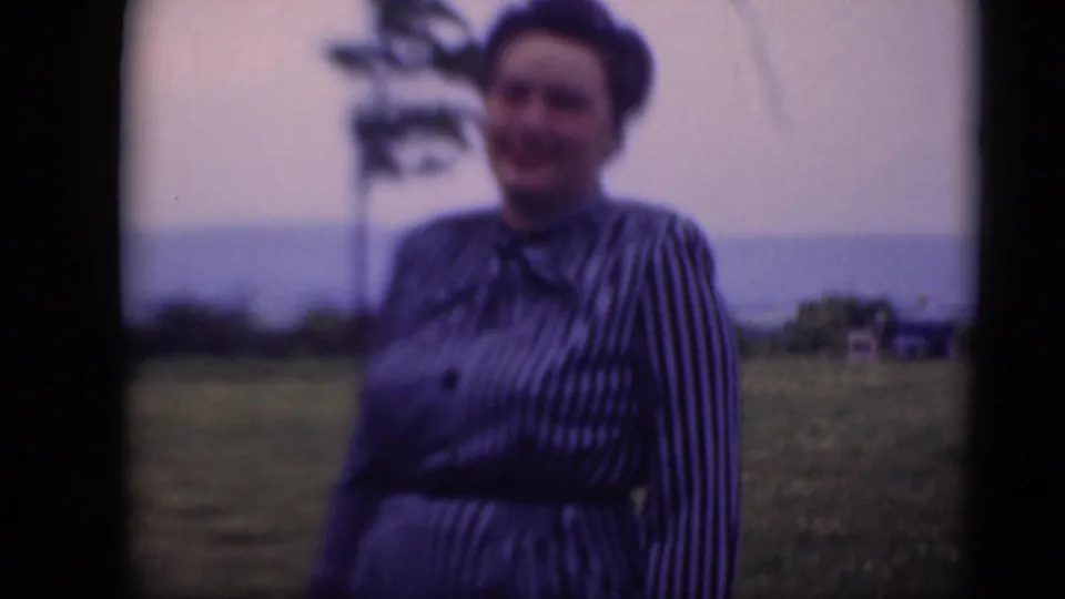 A woman in a belted striped dress stands outdoors in Middletown, Pennsylvania, with a distant tree and pale sky behind her.