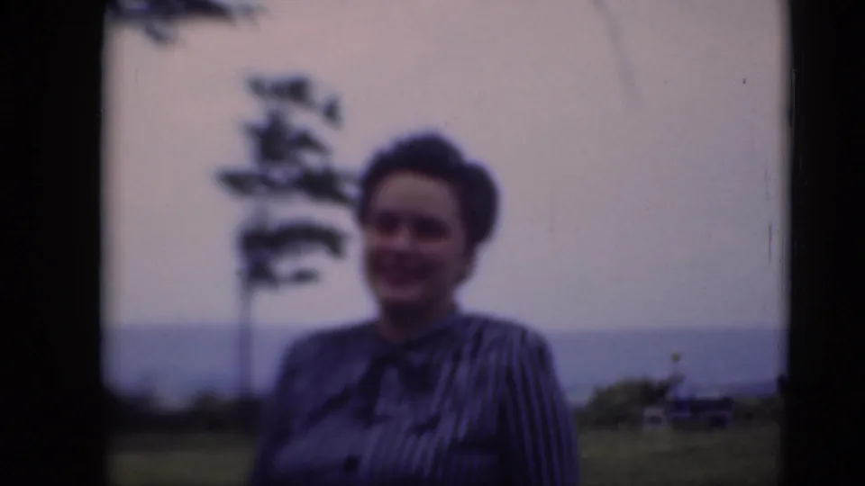 A soft-focus 8mm frame shows the woman smiling outdoors, with a distant tree and open landscape behind her in Middletown, Pennsylvania.