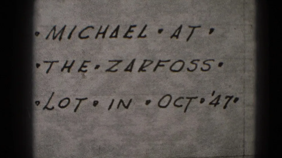 Close-up 8mm frame of a handwritten note naming Michael, the Zarfoss lot, and Oct '47, from Middletown, Pennsylvania metadata.