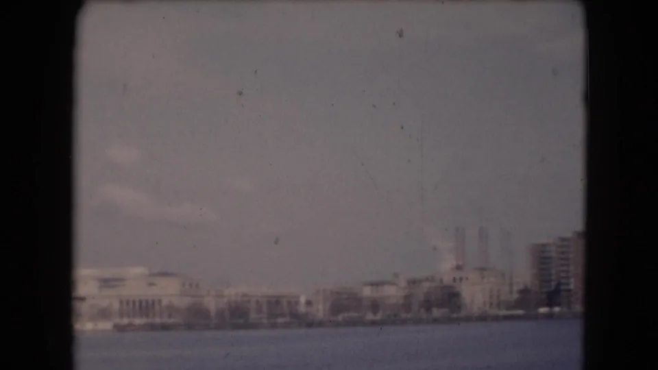 Reported Middletown, Pennsylvania shoreline with low buildings, smokestacks, bare trees, water, and soft 8mm exposure.