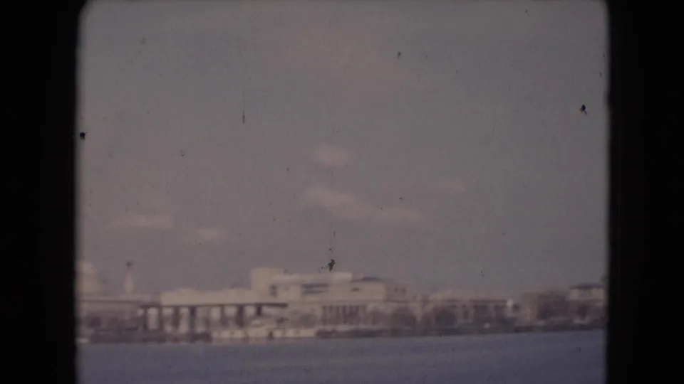 Reported Middletown waterfront view with a broad low building, column-like bays, distant shoreline, haze, and visible 8mm wear.