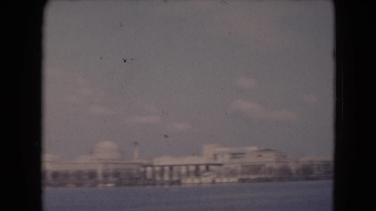 Distant waterfront skyline with domed buildings across open water.