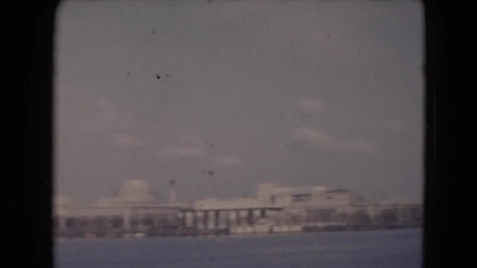 1948 8mm frame showing a distant Middletown, Pennsylvania waterfront skyline with domed structures and low buildings across water.