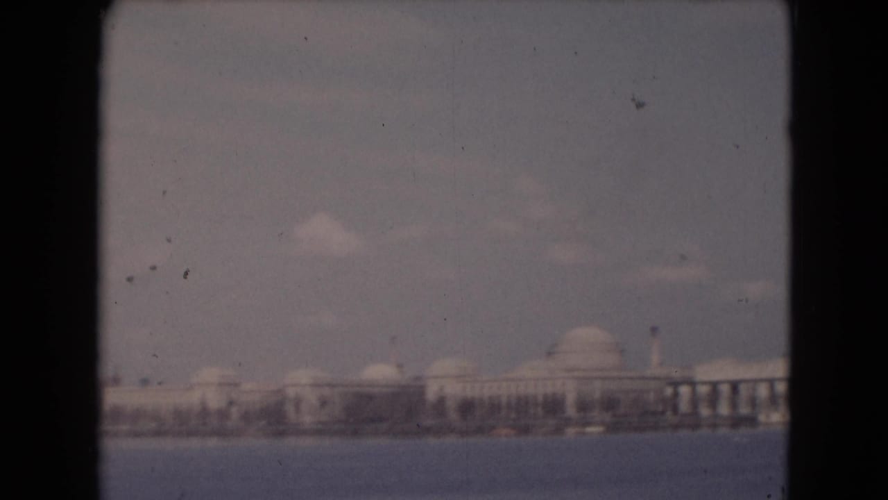 Waterfront buildings and domed structures framed by dark film borders.
