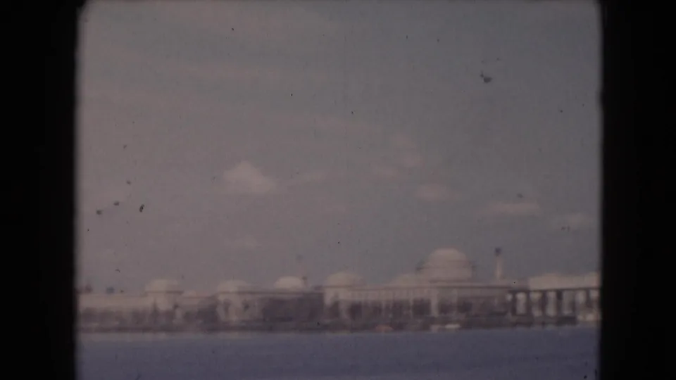 1948 8mm view of distant waterfront buildings in Middletown, Pennsylvania, with domed roof forms and dark film-strip edges.