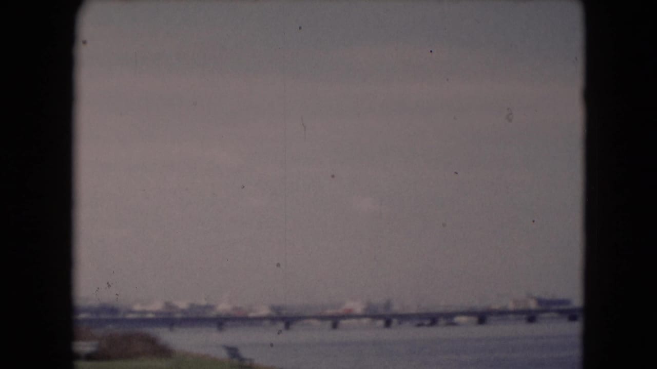 Distant 1940s home-movie view of a long bridge and wide river near Middletown, Pennsylvania, with shoreline forms in soft focus.