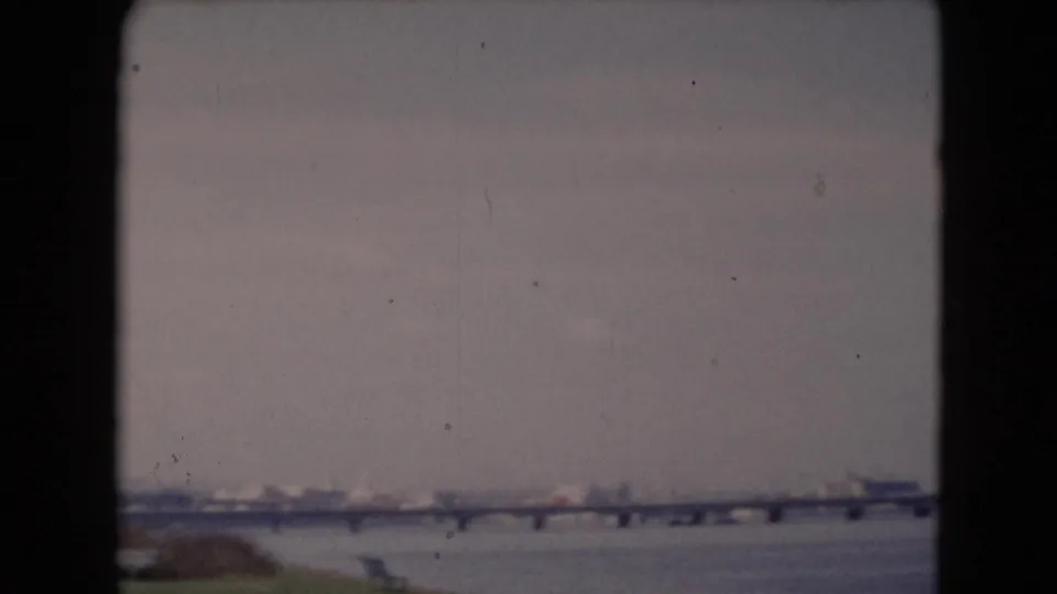 Distant 1940s home-movie view of a long bridge and wide river near Middletown, Pennsylvania, with shoreline forms in soft focus.