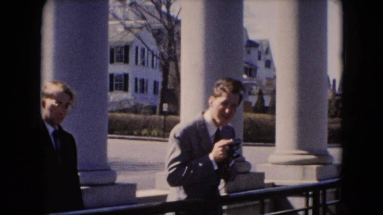 In supported Middletown, Pennsylvania footage, two suited men stand on a columned porch as one holds a small camera.