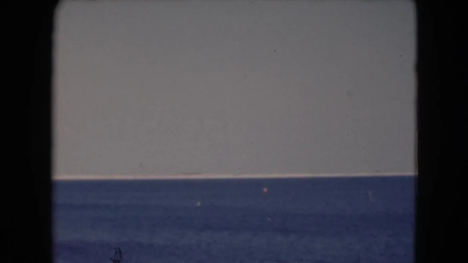 1940s 8mm home-movie view of open blue water and a pale sky, with the horizon held near the center of the frame.