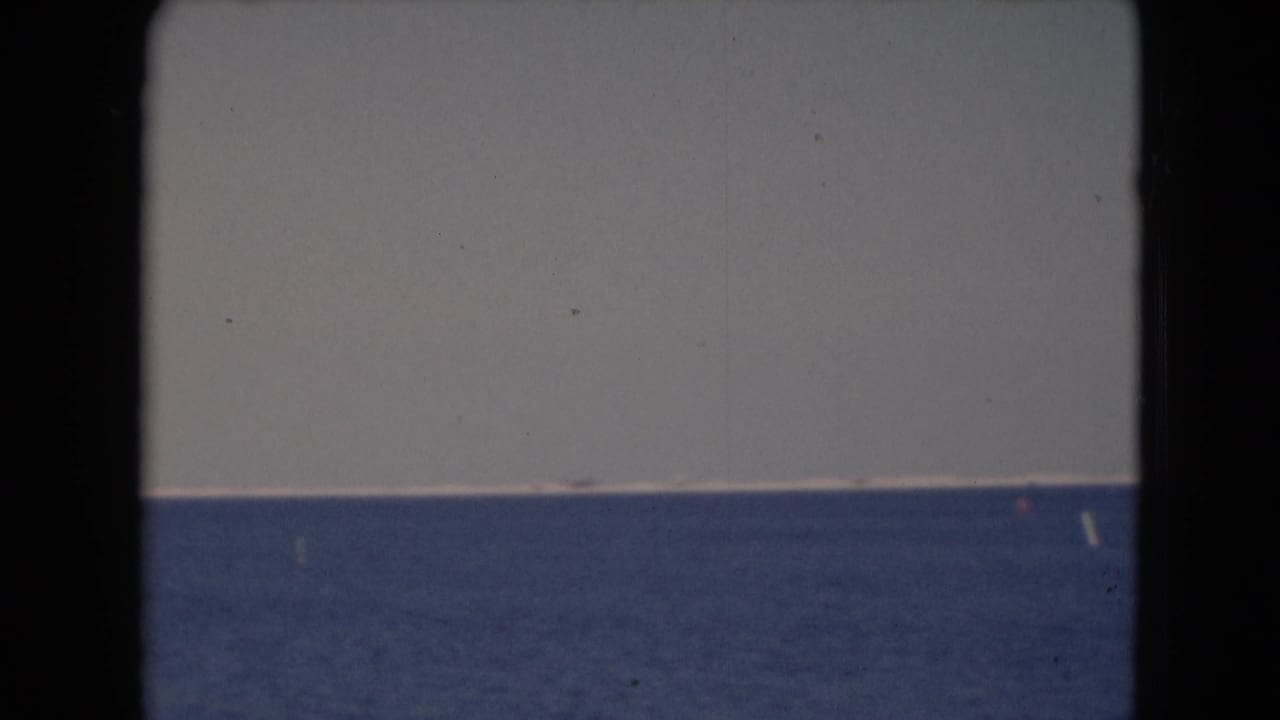 1940s 8mm frame showing a broad water horizon and pale sky from a visitor-shot viewpoint.