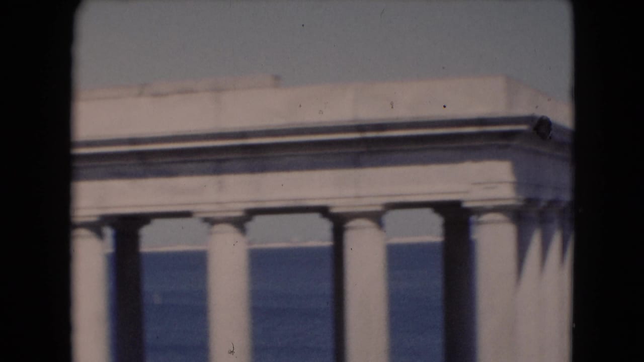 White columned building edge overlooking blue water.