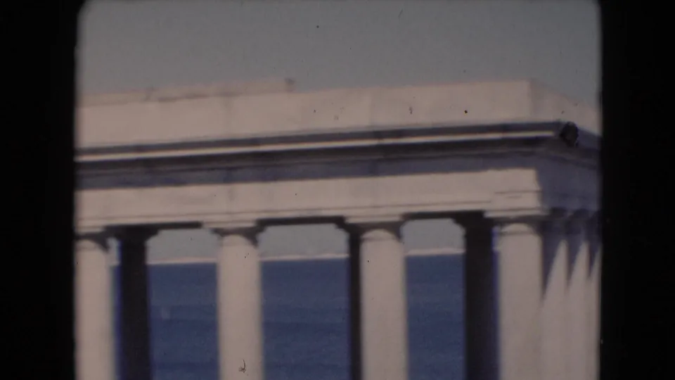 A white classical-style structure with columns appears beside a broad body of water in 1940s home-movie footage.