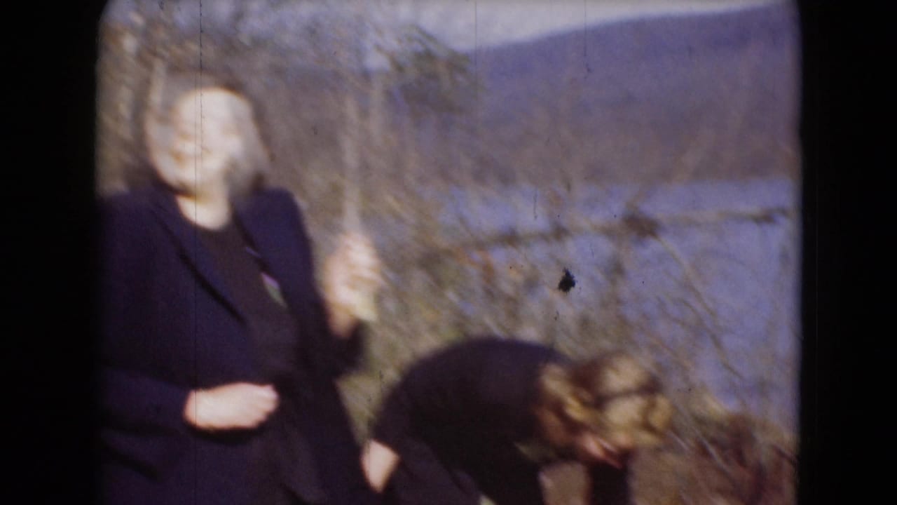A woman gestures toward the camera while another bends down in soft, motion-blurred 1948 lakeside home-movie footage from Middletown.