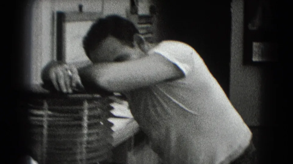 In the final frame, the man leans on his folded arms near stacked items in a softly focused private interior.