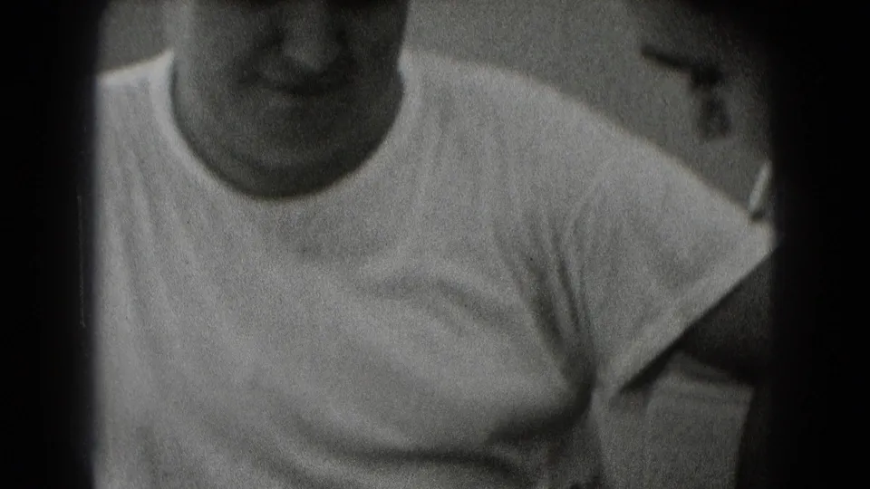 Close black-and-white 8mm frame of an adult man in a white T-shirt seated indoors in Middletown, Pennsylvania archival footage.