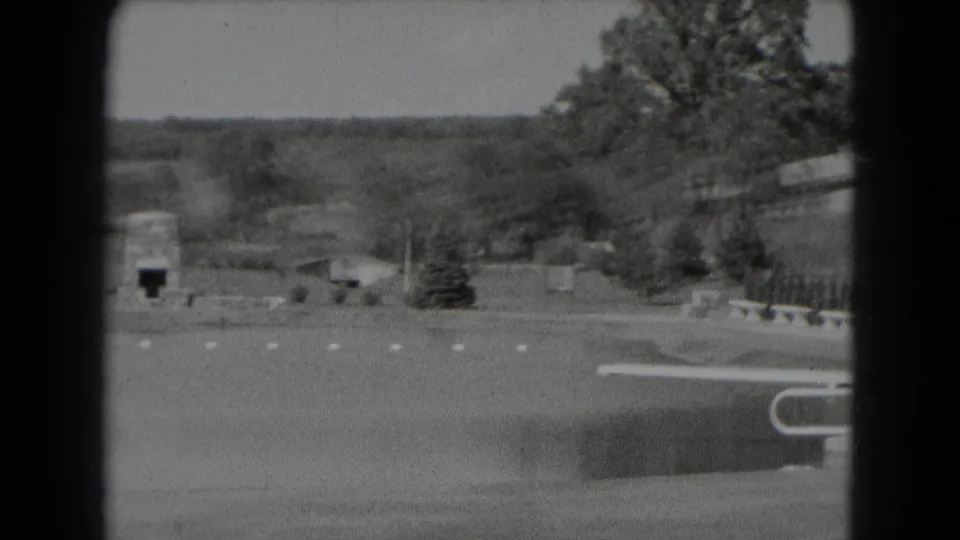 1975 Middletown, Pennsylvania frame with water in front of open grounds, a low wall, trees, benches, and a small stone structure in the distance.