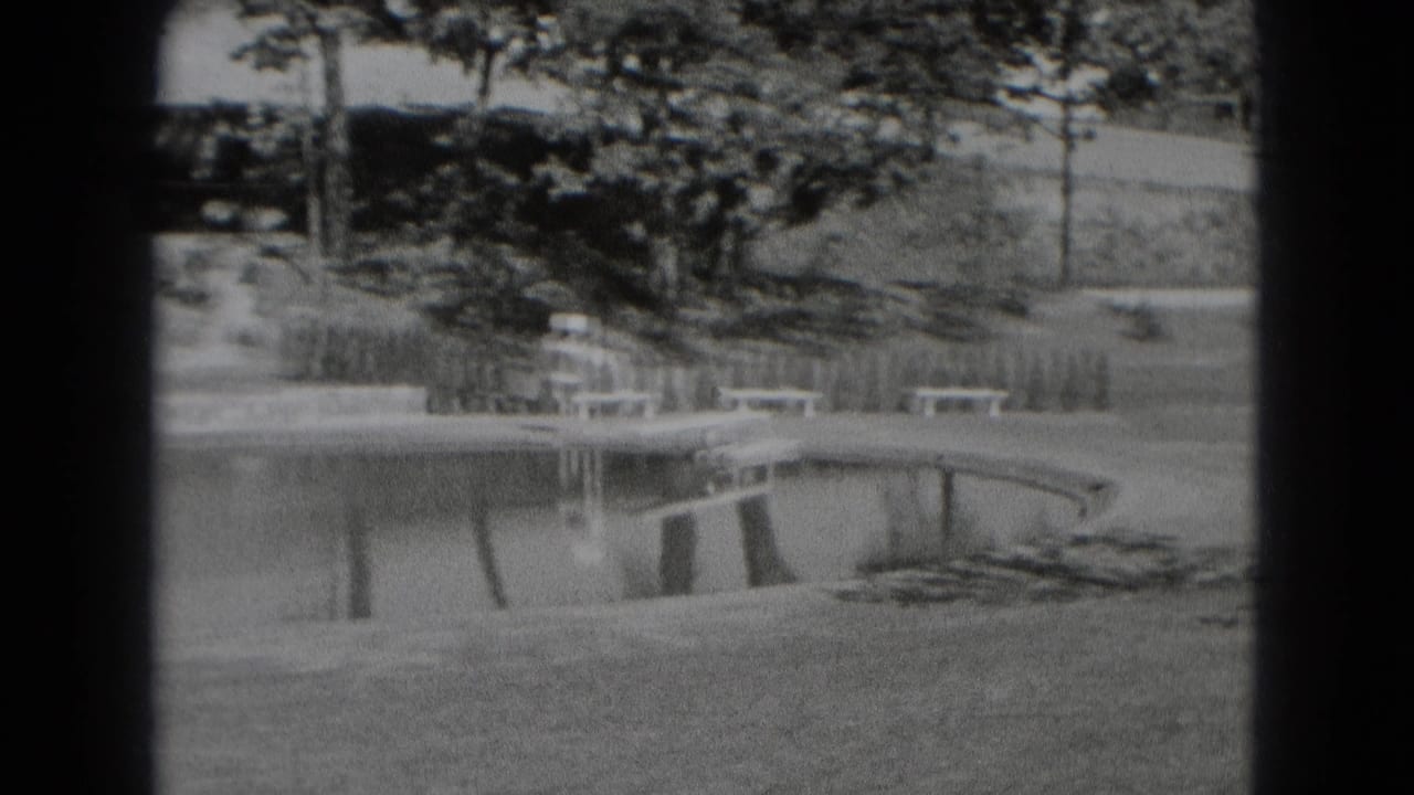 Black-and-white 8mm view of a landscaped creek edge in Middletown, Pennsylvania, with benches, trees, shrubs, and a curved shoreline.