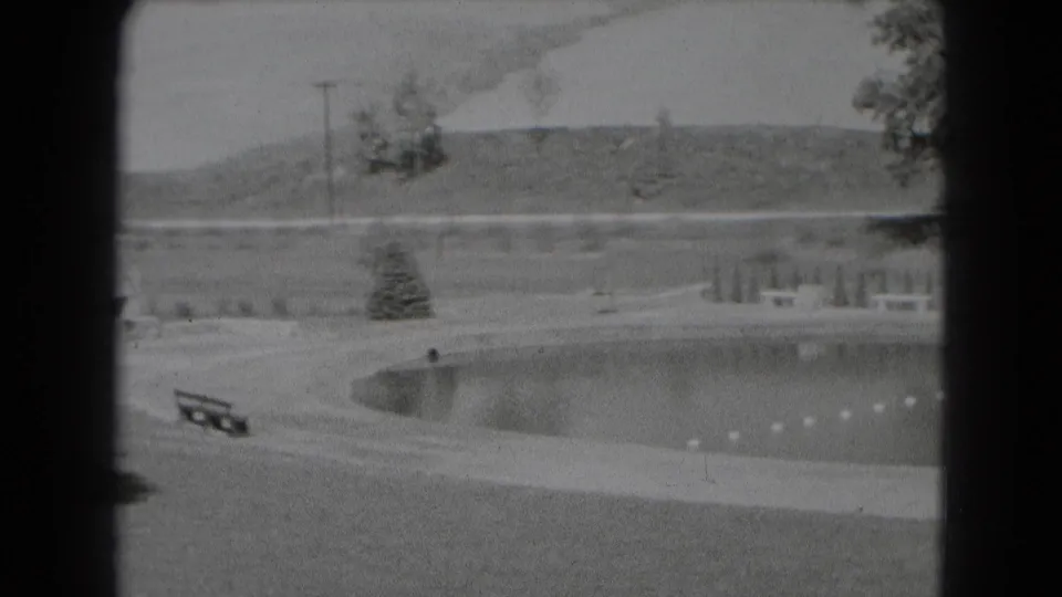 The home-movie pan widens across the Middletown recreation area, with benches, open lawn, a roped lagoon, small evergreens, and a hill in back.